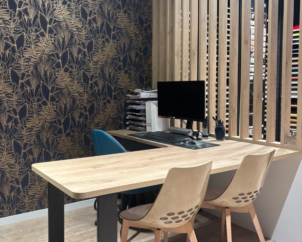Bureau en L chêne naturel avec retour bleu nuit et pieds rectangulaires noirs, installé dans le showroom d’Agen