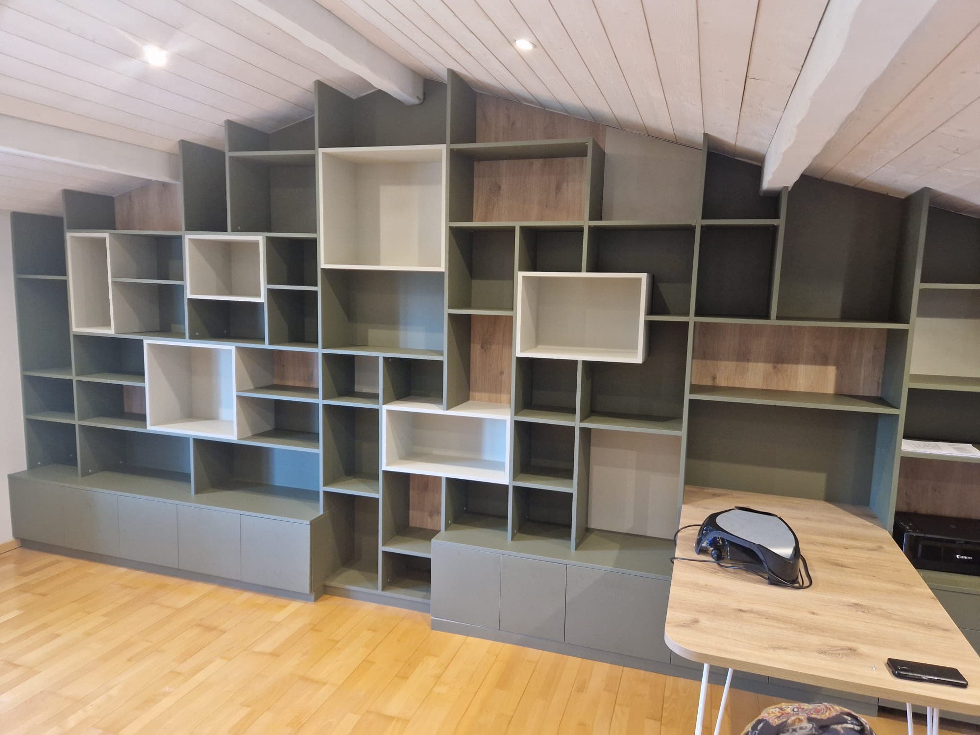 Bibliothèque sur mesure vert olive épousant la pente du plafond à Layrac