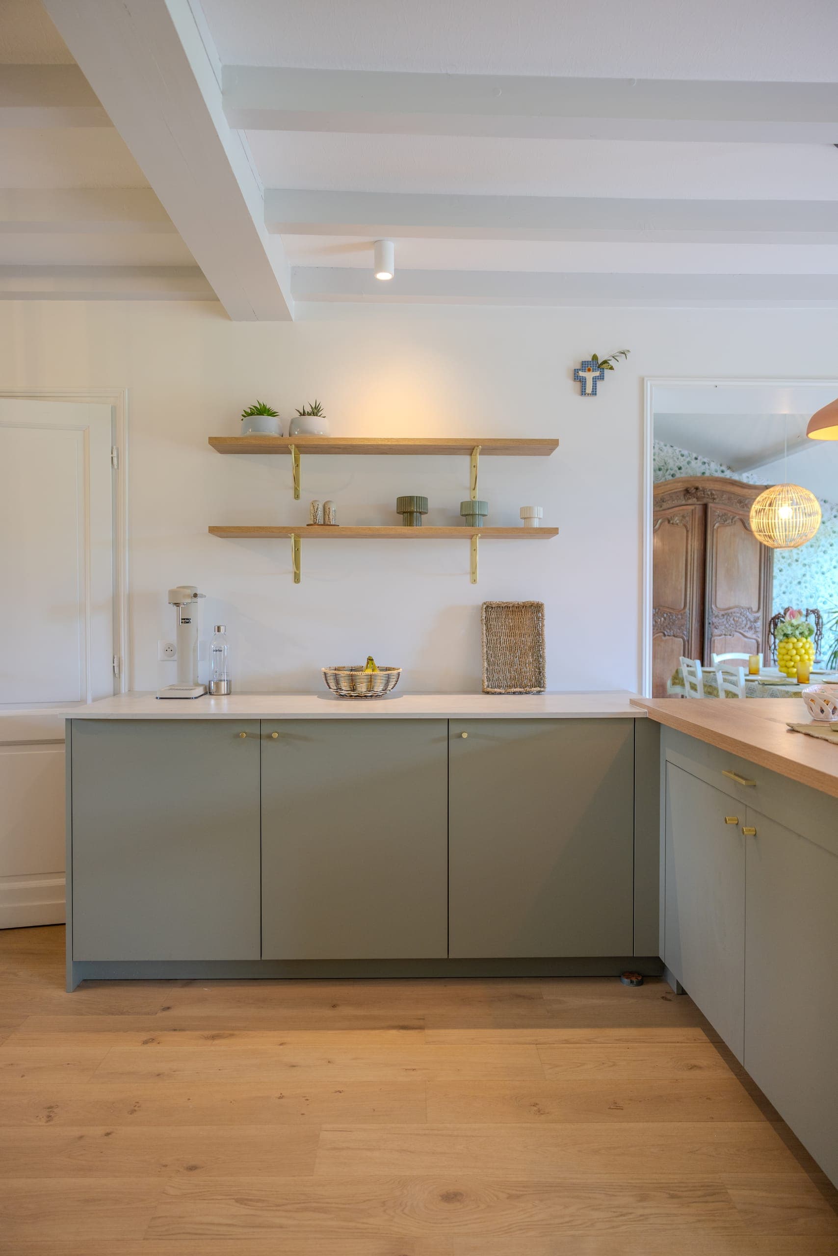 Buffet bas façades vert minéral, poignées dorées, étagères bois et applique laiton, plan clair