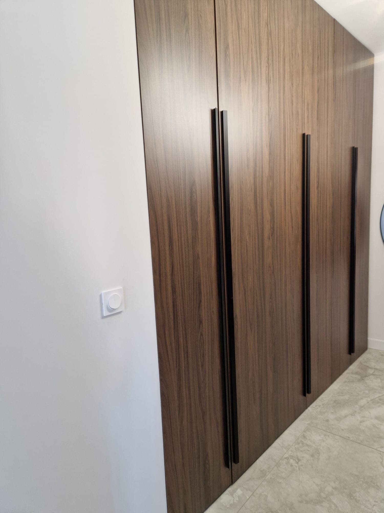 Portes de placard battantes noyer foncé avec grandes poignées bois dans un couloir