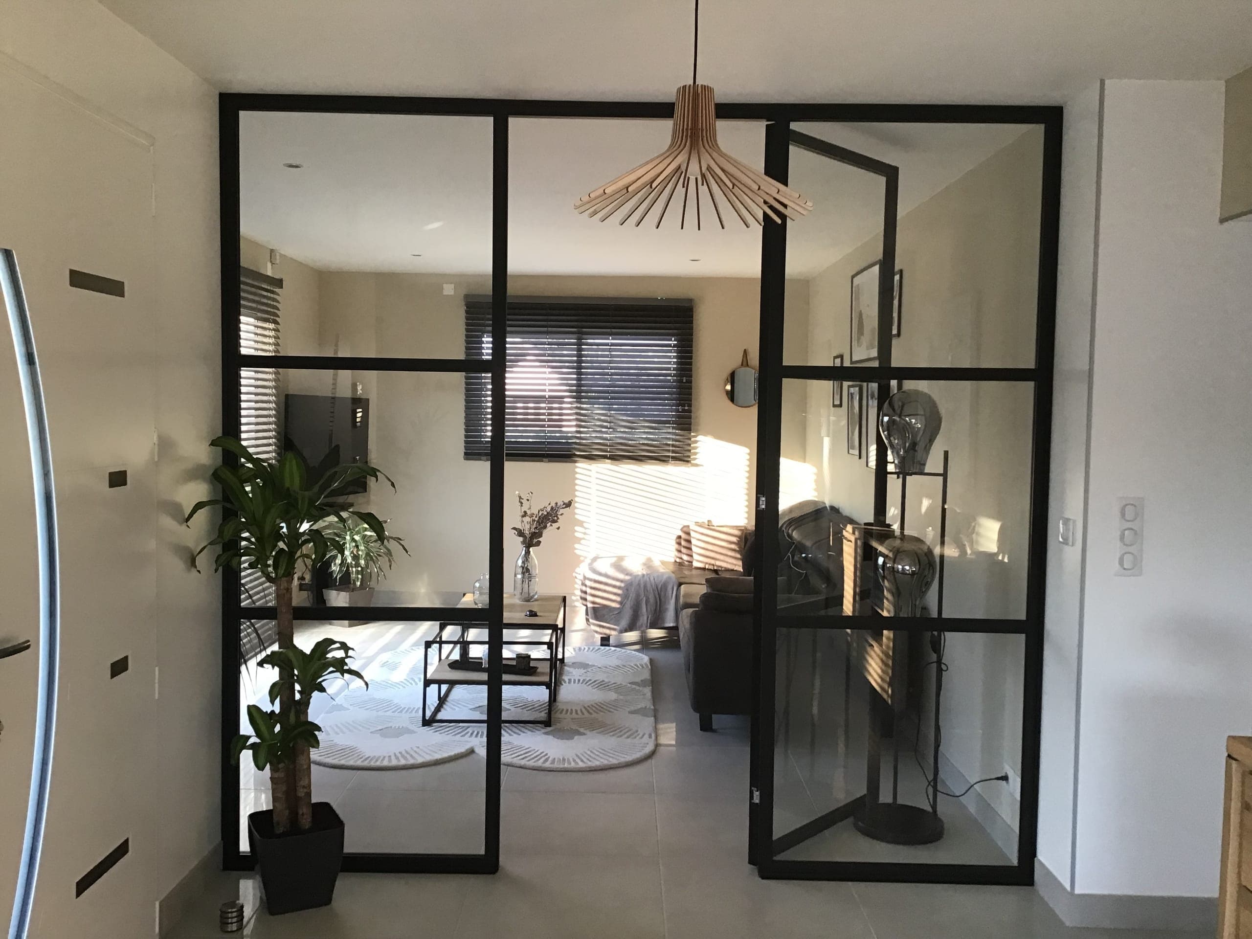 Verrière intérieure aluminium noir avec porte ouvrante entre entrée et salon