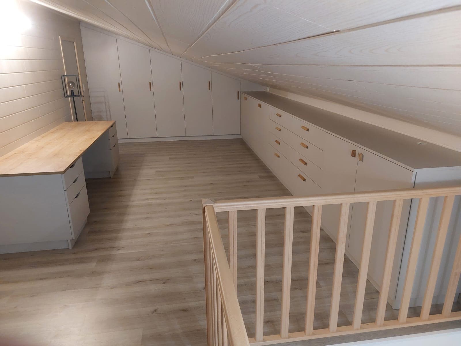 Mezzanine sous pente aménagée sur mesure : plan de travail en bois, rangements cachemire le long du rampant et dressing intégré, sur les coteaux d’Agen